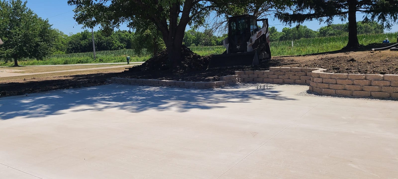 New stone retaining wall and poured concrete pad on a Kansas City property