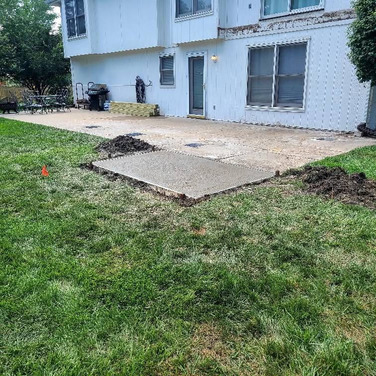 Fresh concrete pad and regraded soil at a home's foundation
